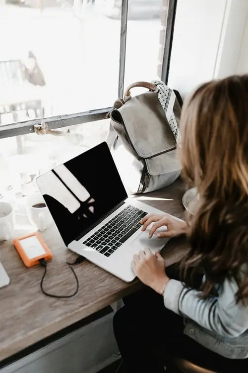 Free-to-start easy online side hustles for college students. Image shows a college-aged woman working online, typing on a laptop.
