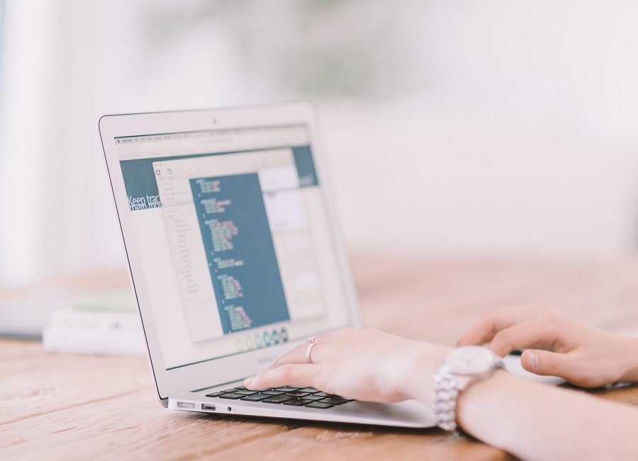Woman's hands type in a notebook, she's learning how to improve WordPress security in 9 steps using a WordPress security checklists, searching for the best WordPress security plugins, and hardening WordPress.