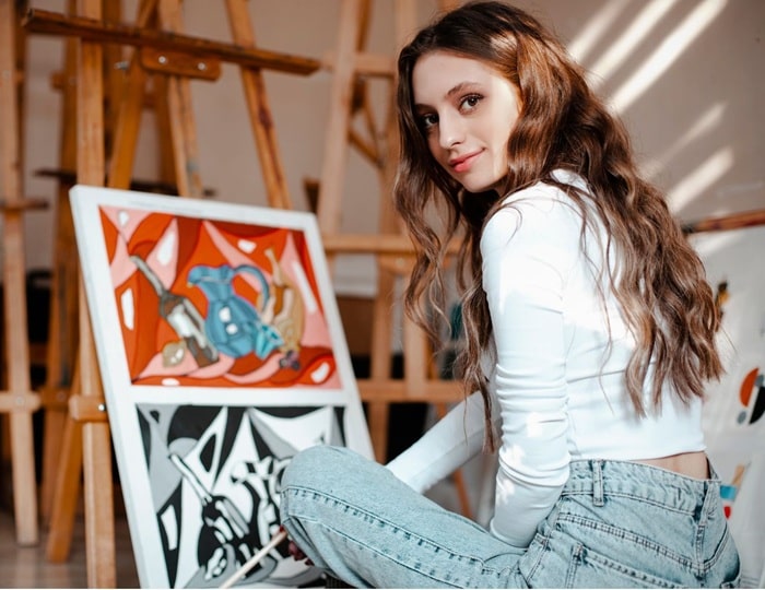 Artist painting a canva, thinking about selling her art to earn money online on the best platforms to sell art online.
